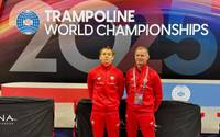 Trener z zawodnikiem, w dresach reprezentacji Polski, stoją na tle ścianki z napisem "World Trampoline Championschips 2025"