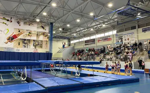 Sala zawodów - na pierwszym planie trampoliny ze skaczącym zawodnikiem, w tle pełne trybuny.