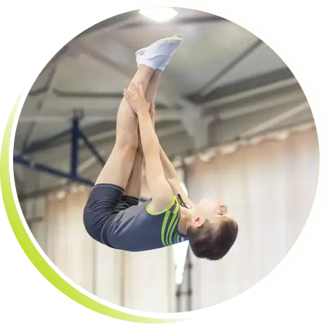 Młody zawodnik w klubowym stroju wykonuje salto proste