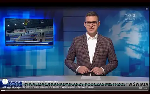 Zrzut ekranu - prezenter TVP3 Katowice w studiu, za nim na ekranie kadr z treningów w skokach na trampolinie.