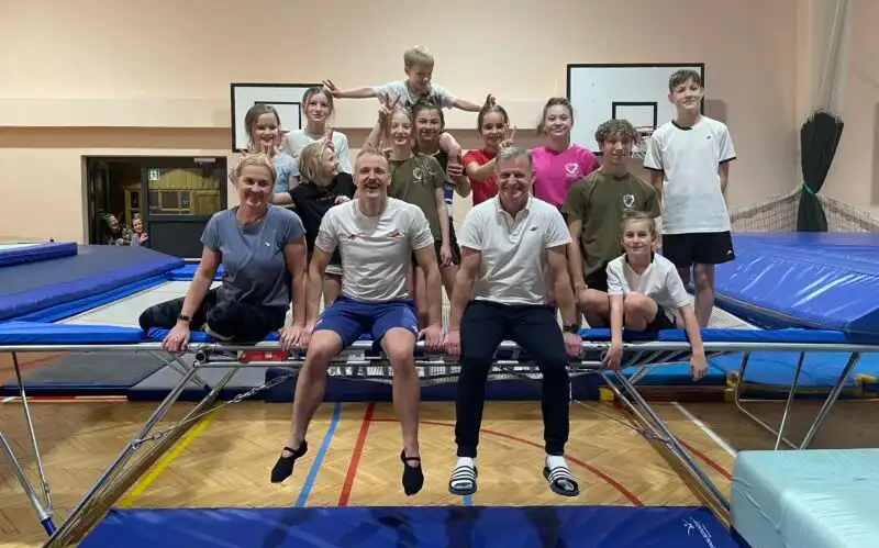 Artur Zakrzewski i Janusz Kruk siedzą na trampolinie w grupie zawodników
